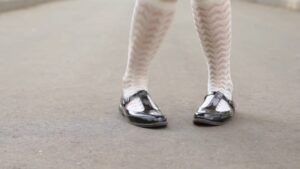 A pair of feet clad in white patterned tights and black patent leather shoes on a concrete surface feature in a Biteable video maker project.