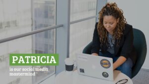 A woman with curly hair, working on a laptop with stickers, sitting in a green chair by a window in an office, using Biteable video maker, with text "Patricia is our social media