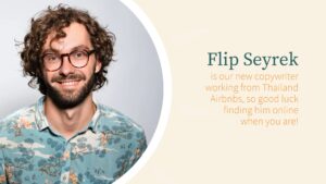 Portrait of a smiling man with curly hair and glasses, wearing a floral shirt, featured in a Biteable video maker presentation, introducing him as Flip Seyrtek, a copywriter.
