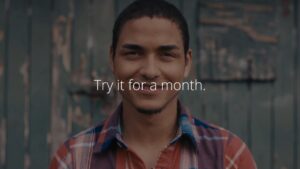 Young man smiling against a wooden background with the text "try Biteable video maker for a month.
