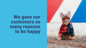 A French bulldog in a colorful jacket sits on gravel, tongue out, next to a wall with red, white, and blue stripes. Text reads, "We gave our customers so many reasons to be happy.