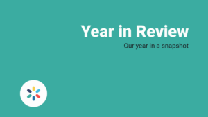 Teal background with white text that reads "Year in Review" and smaller text "Our year in a snapshot," with a circular logo in the lower left corner.